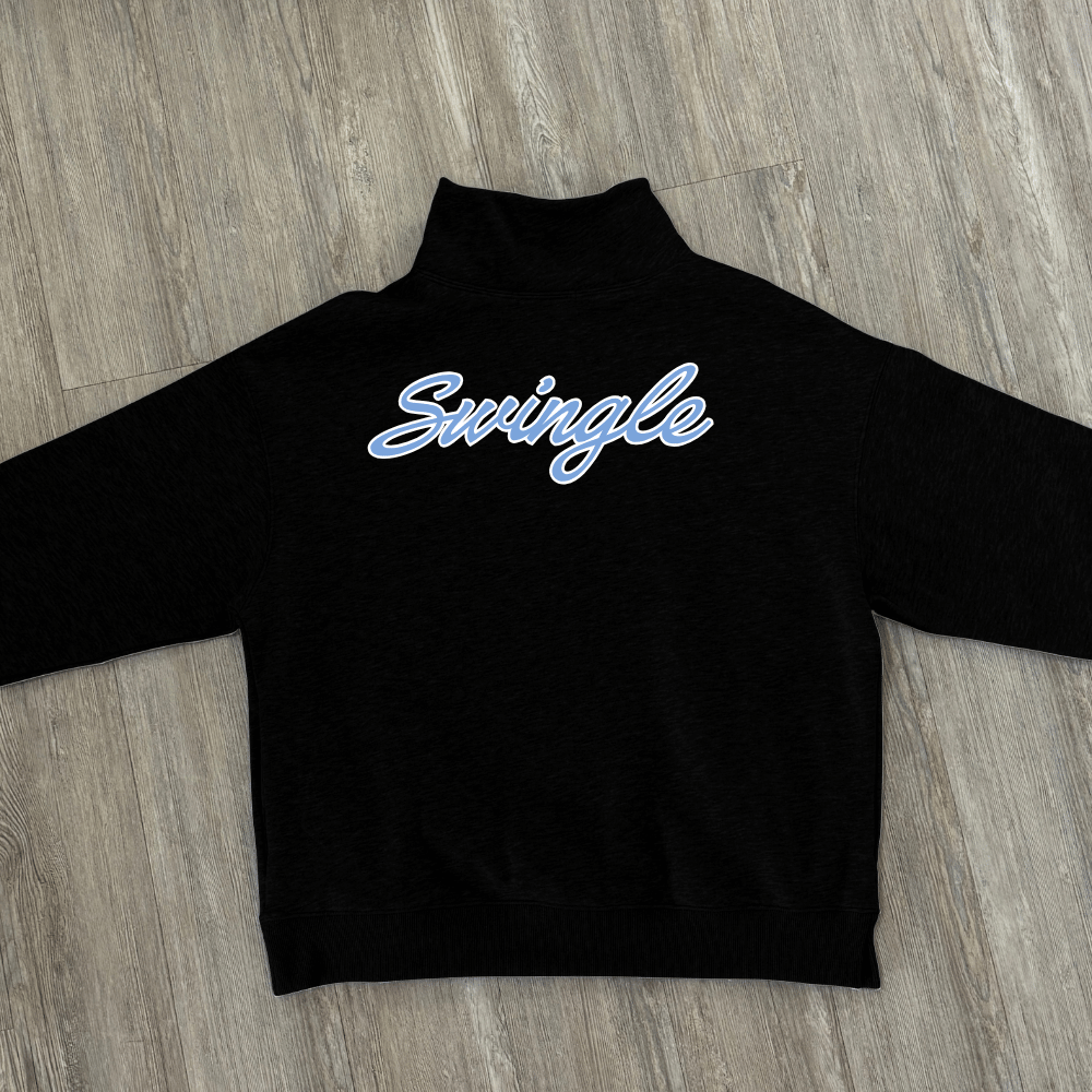 A black long-sleeve mock neck sweatshirt with custom name in a light blue cursive script across the back, laid flat on a gray wood-look floor.